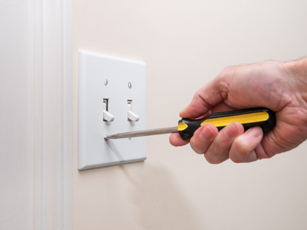 stock-photo-male-electrician-repairing-wall-light-switch-panel-handyman-using-screwdriver-to-install-screw-on-1587076678