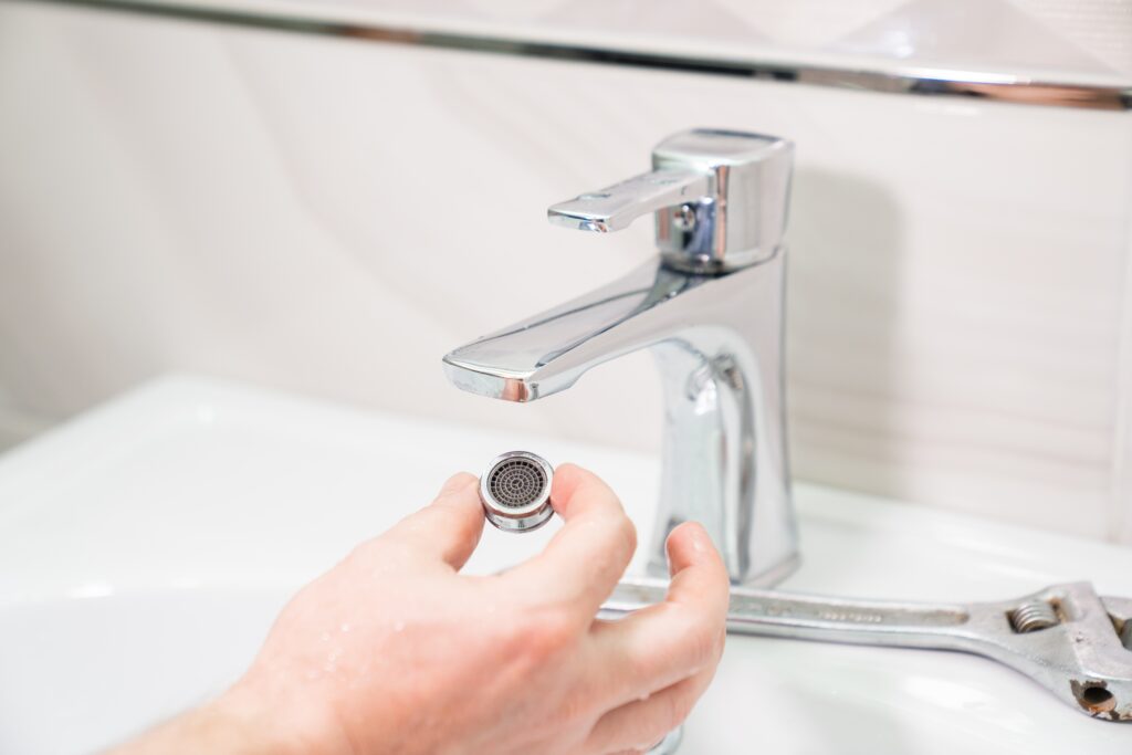 stock-photo-the-repairman-removes-and-cleans-the-aerator-from-water-stone-and-rust-special-nozzle-on-the-spout-2149500685