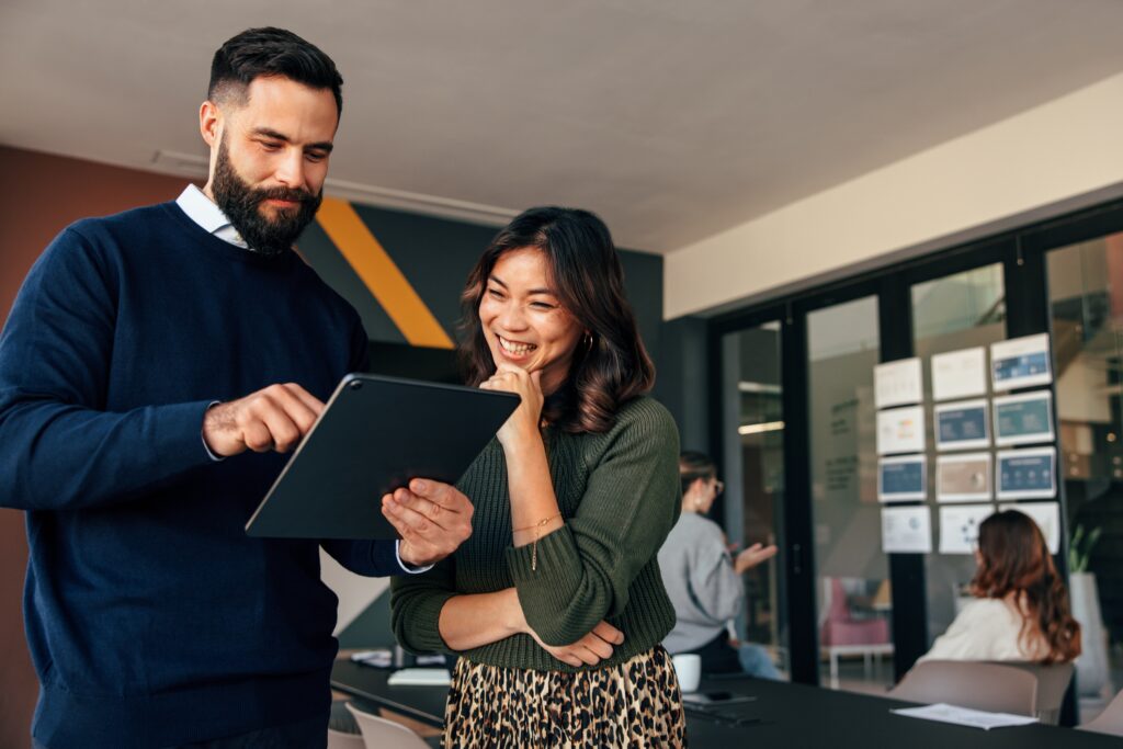 stock-photo-happy-business-colleagues-using-a-digital-tablet-in-a-boardroom-two-young-businesspeople-having-a-2163200889