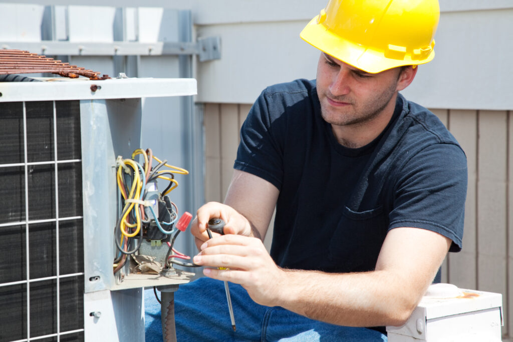 stock-photo-young-repairman-fixing-an-industrial-air-conditioning-compressor-27344143