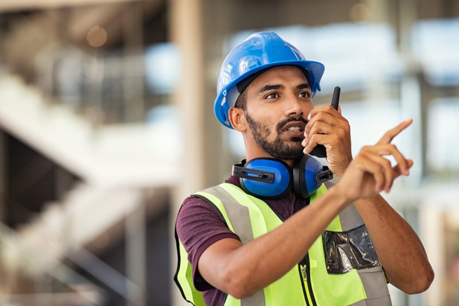 stock-photo-young-mixed-race-supervisor-instructing-workers-using-walkie-talkie-at-construction-site-2054430389