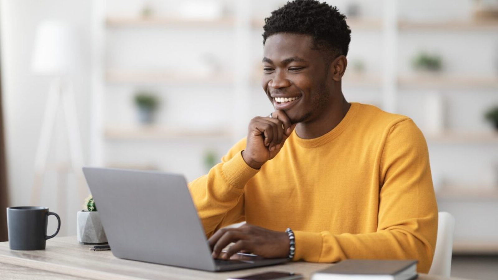 stock-photo-happy-black-guy-project-manager-sitting-at-workdesk-at-office-typing-on-laptop-keyboard-and-2100706477