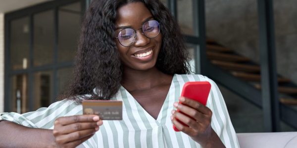 stock-photo-happy-young-black-african-woman-customer-shopper-holding-credit-card-using-cell-phone-mobile-app-2055003335